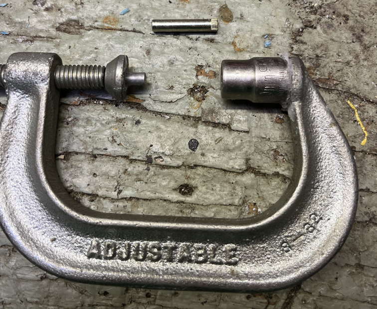 Hinge pin removal device, metal standoff on left, hex socket on right. Pivot pin above tool, knurled side to the right.